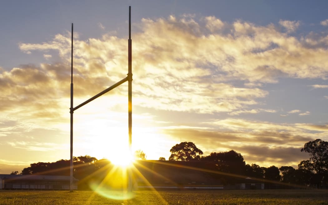 Goal posts for football, rugby union or league on field at sunset.