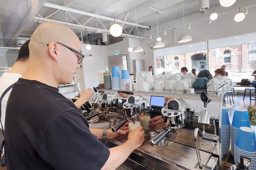 A man pictured from the back making coffee using the machine.