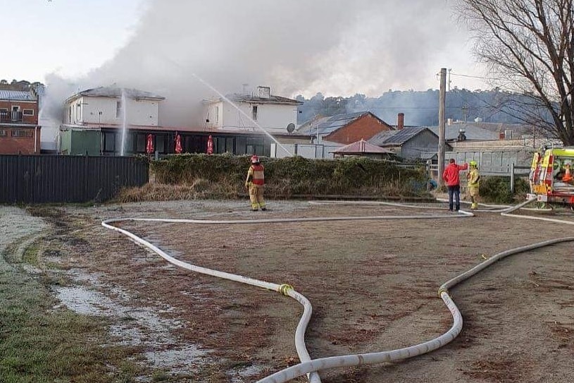 Firefighters working at a building with smoke.