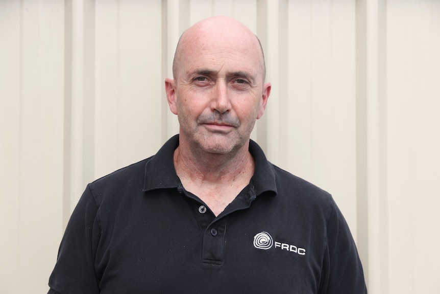 Headshot of bald white man wearing a black t-shirt.