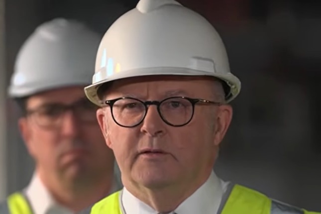 Close up of Anthony Albanese wearing a white hard hat and glasses.