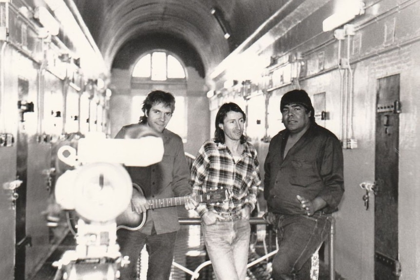 Uncle Roger with two other musicians inside a jail compound, black and white photo.