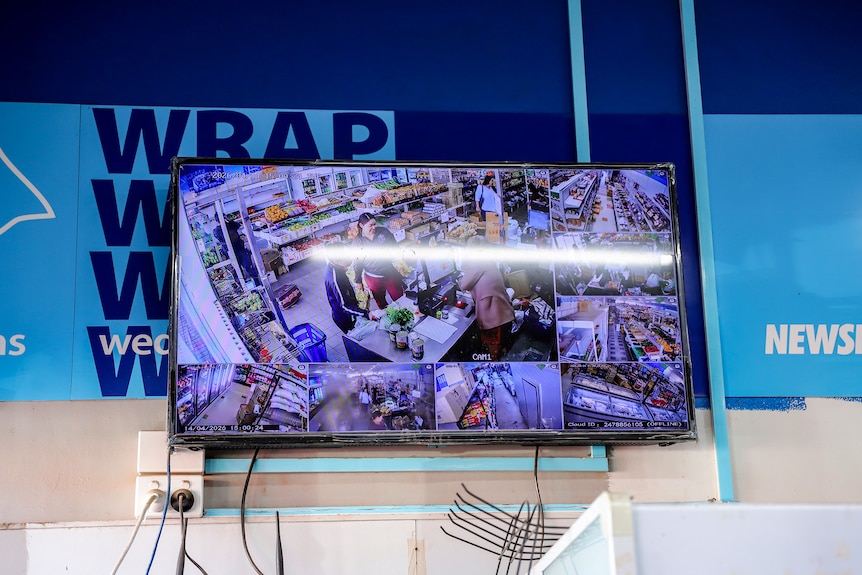 A television screen with multiple window panes showing security camera footage from inside a supermarket