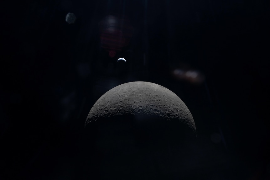 A faint view of a crescent Earth above the horizon on the Moon’s far side