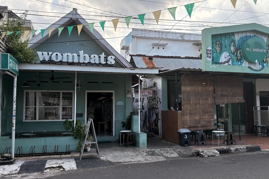 A green house with Wombats name in the roof and two people sitting down.
