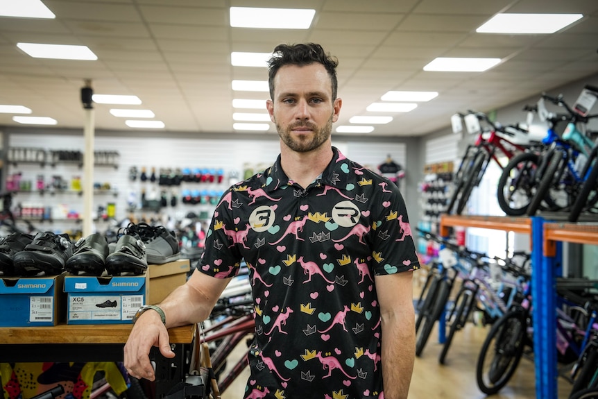 A man in a bike shop looks at the camera.