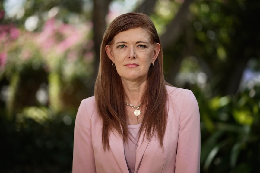 a woman with red hair in a pink jacket