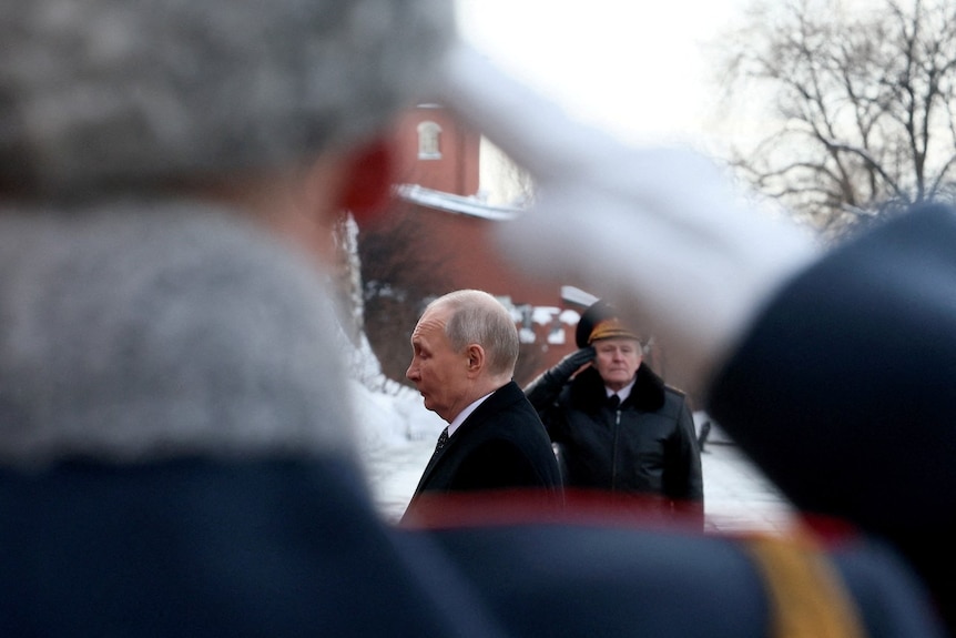 A man in a suit seen walking near soldiers