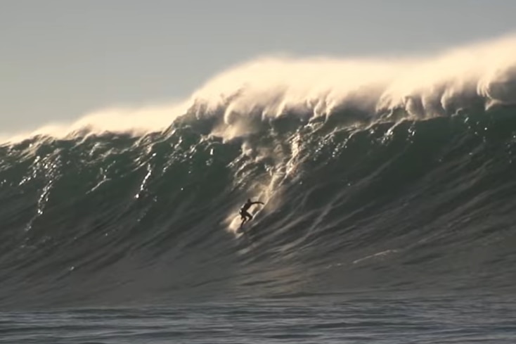 Nathan Bartlett surfing in the middle of a massive wave on the east coast. He looks tiny in comparison to the wave.