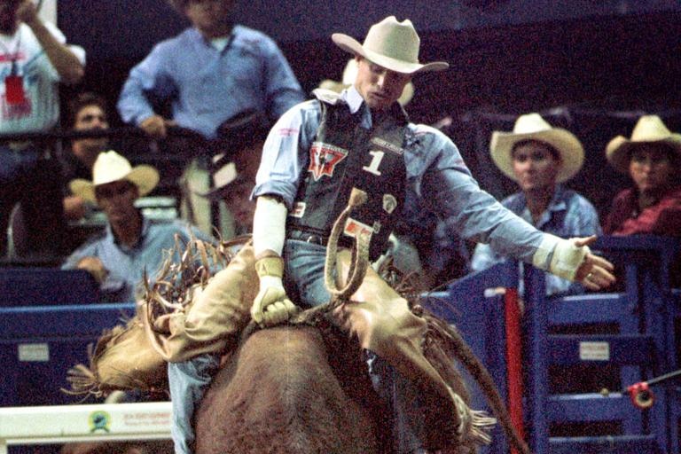 A man on a bucking bull.