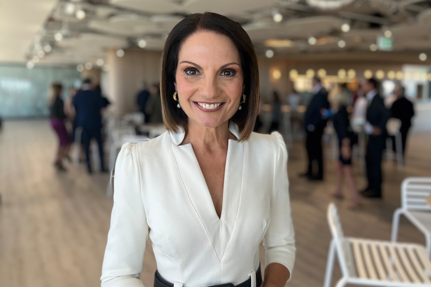 Smiling woman in white dress at event.