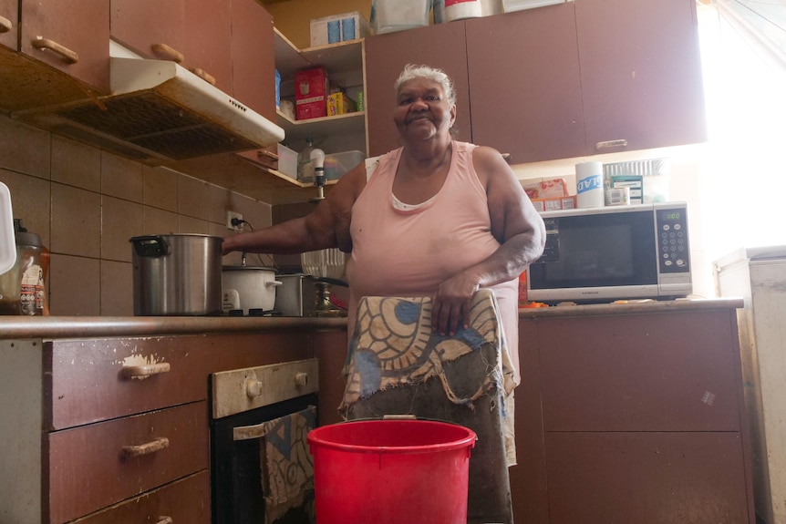 An older woman with grey hair in her kitchen.