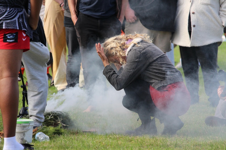 a women ducks down to put smoke on her