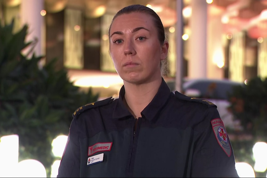 A woman with dark hair pulled back behind her head in a navy uniform with a badge that says "paramedic".