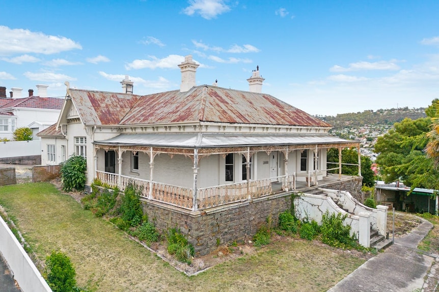 rusted old roof on an a century-old iron home with bluestone base, blue skies