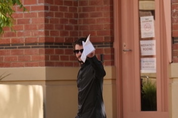 a man with dark hair outside a Victorian court