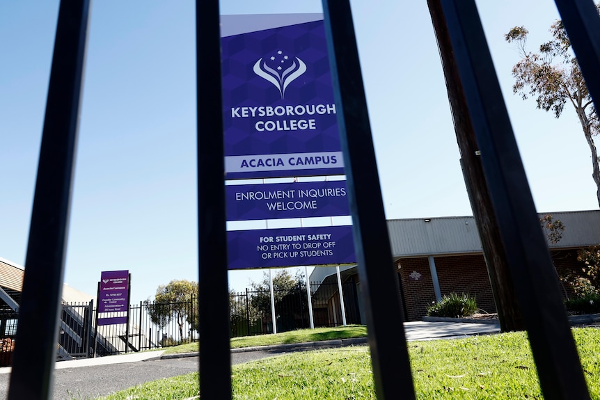 A sign that says "Keysborough College", as seen through a metal fence.