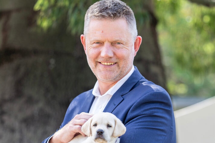 A man in a blue suit holding a puppy