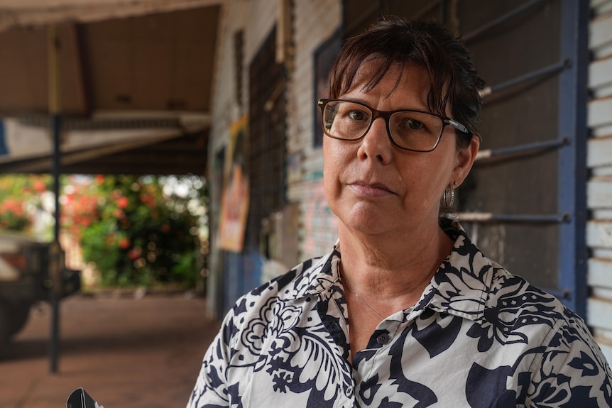 A woman on right of screen wearing glasses looking at camera