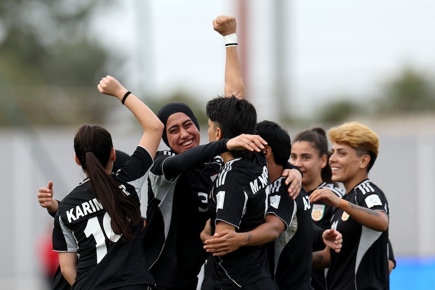 Members of the Afghan Women United football team gather and celebrate after scoring a goal