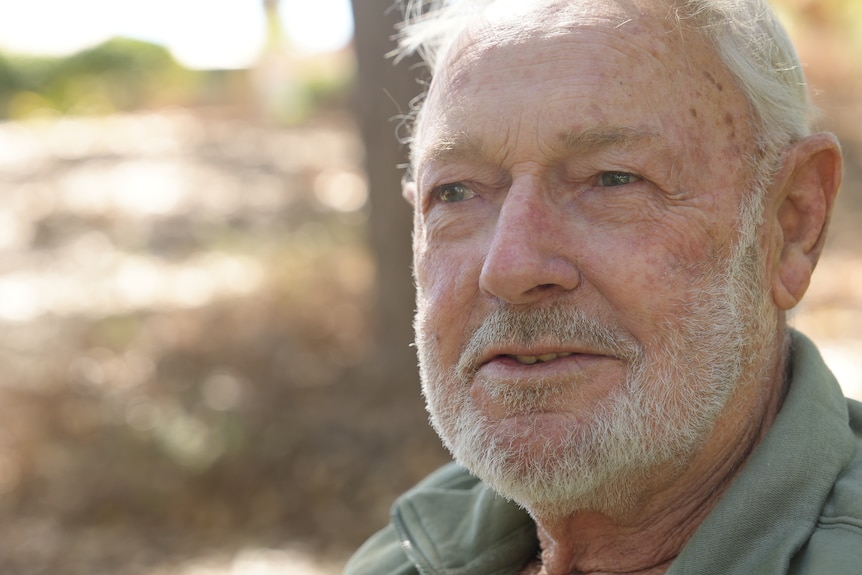 CLose up of a man with a white beard and green shirt.