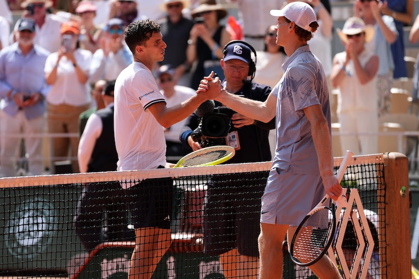 Juan Manuel Cerundolo shakes hands with Jannik Sinner at the net at French Open.