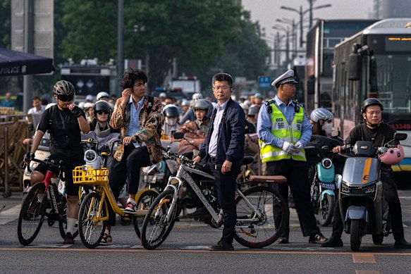 Commuters wait at a traffic light next to a police officer near Tiananmen Square, as the city gets ready to welcome the US president.