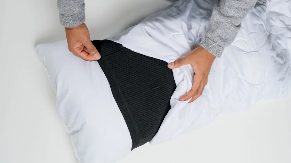 White pillow with black sleeve in the middle, as a pillow case is pulled over.