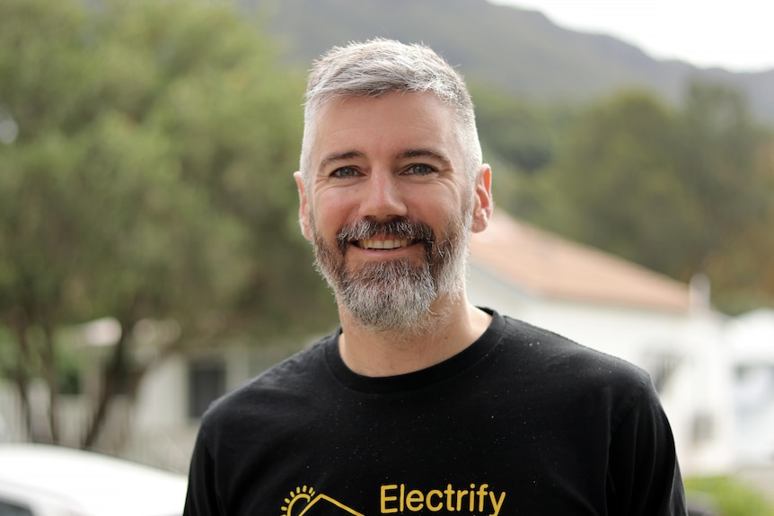 A headshot of Francis smiling outside and wearing a black t-shirt.
