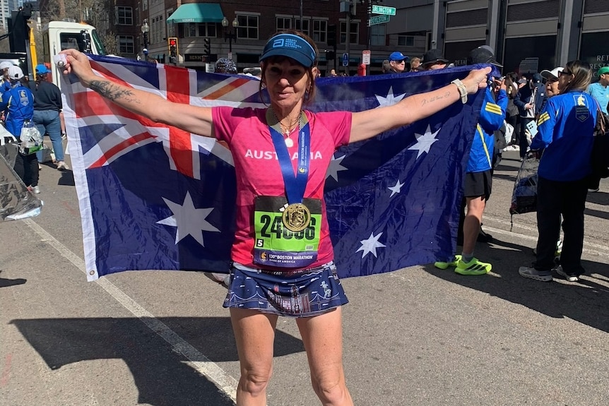 A woman holding an Australian flag with a medal around her neck.