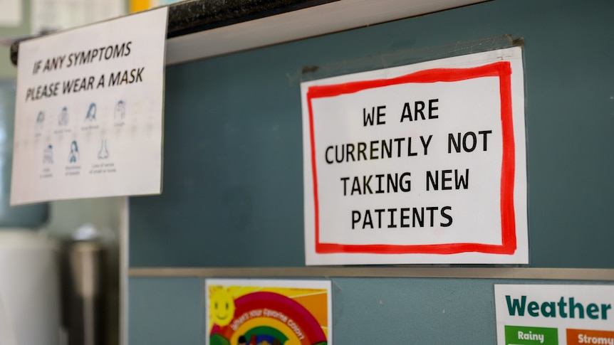 A sign that says WE ARE CURRENTLY NOT TAKING NEW PATIENTS stuck on a desk counter next to other flyers.