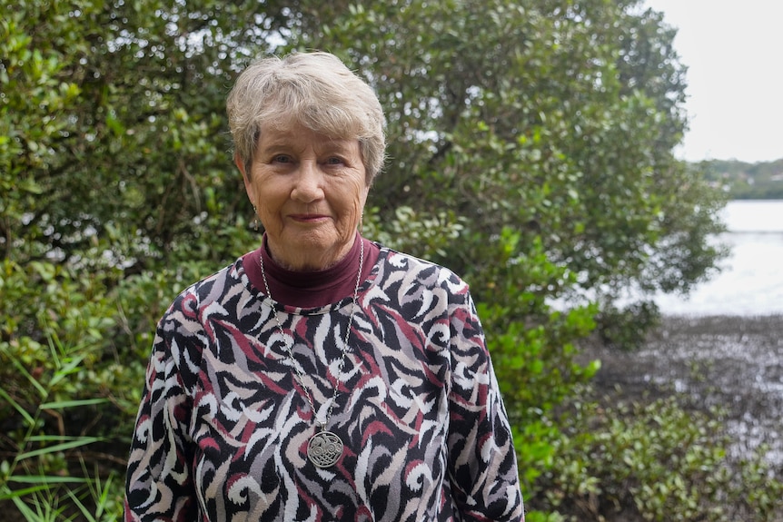 an older woman standing in front on mangroves
