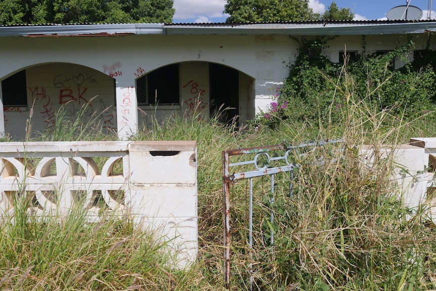 A single-level house with an unkept lawn at the front.