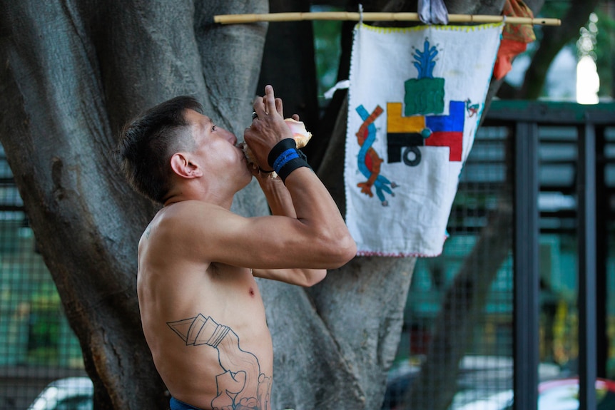 A man blows a conch