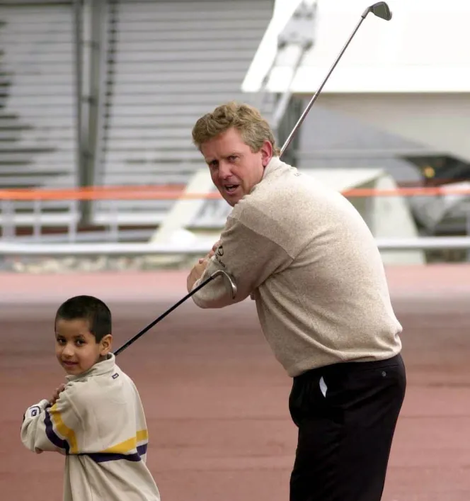Five-year-old Aaron Rai and golfer Colin Montgomerie holding golf clubs at the Millennium Dome.