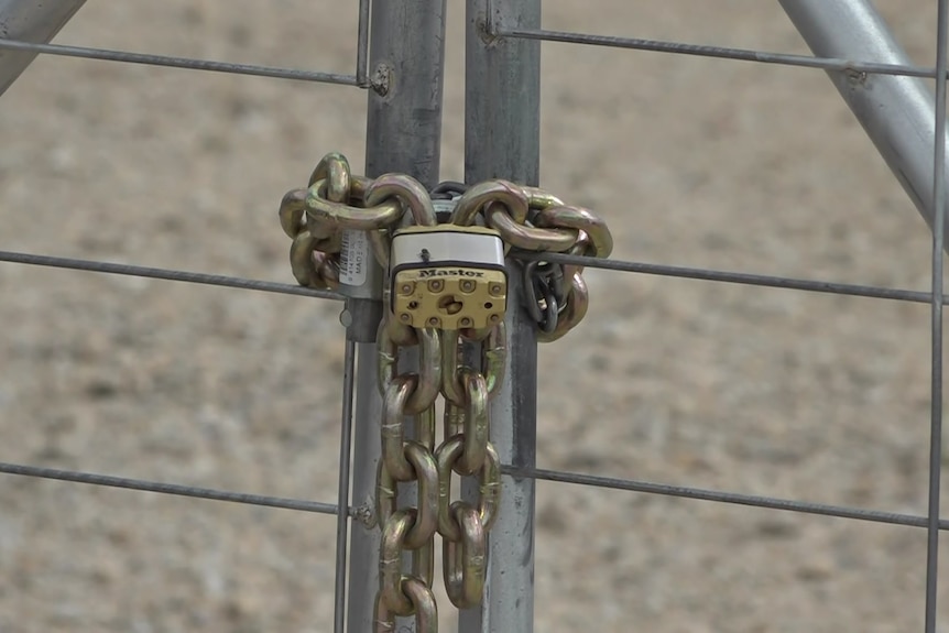 A padlock and chains hangs from a gate