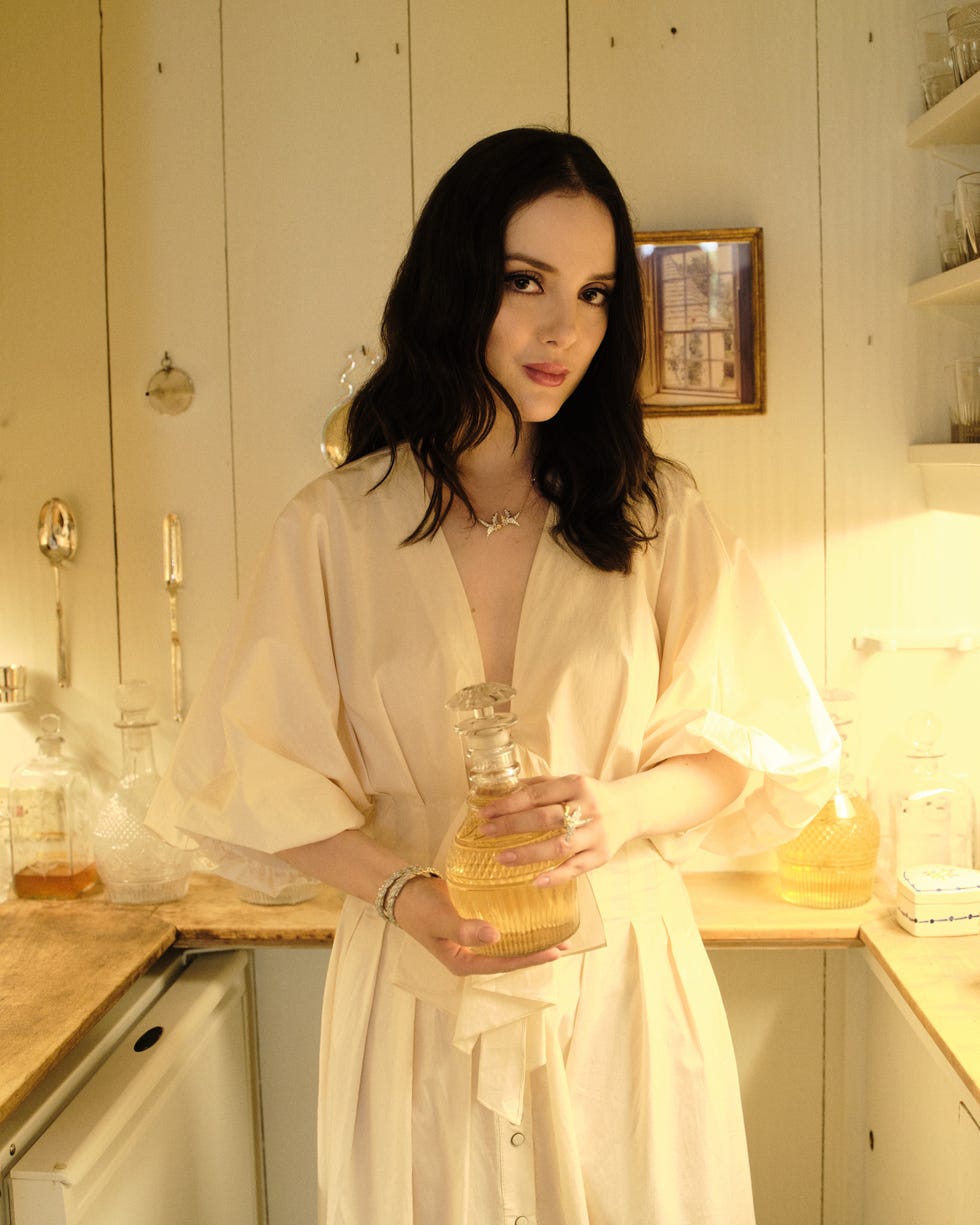 Person holding a glass decanter in a kitchen setting.