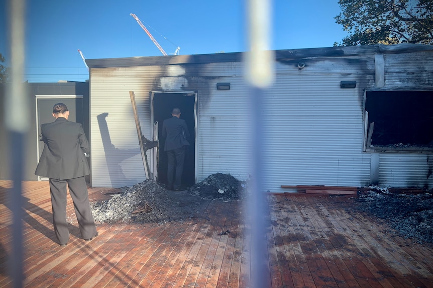 Fire cause investigators enter a burnt out building