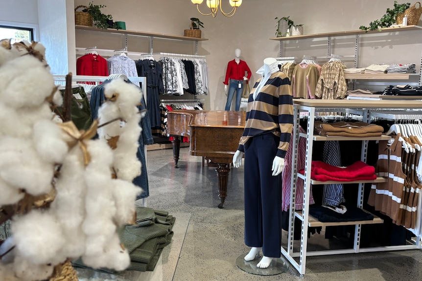 The interior of a clothing store with mannequins and racks. 