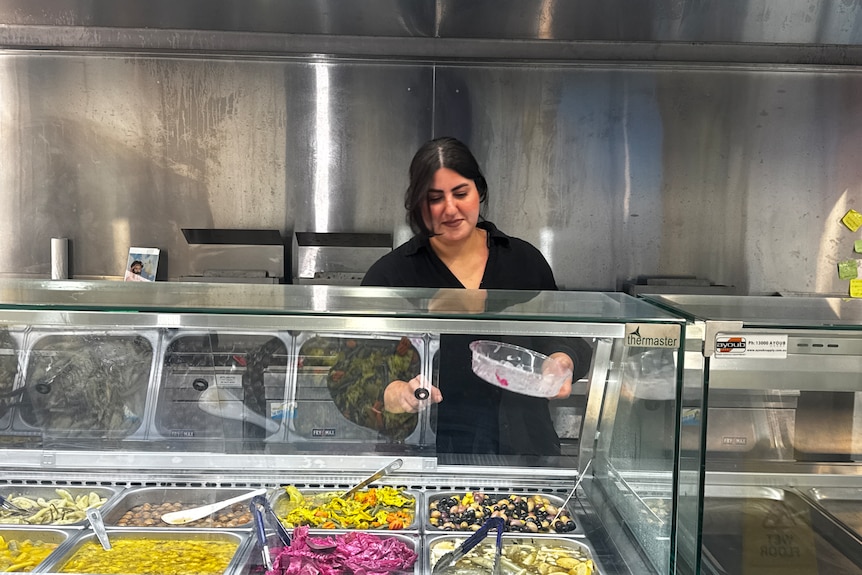 A woman behind a counter serving food.