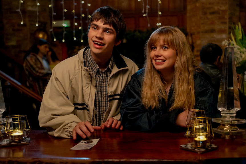 A young man and woman stand at a bar.
