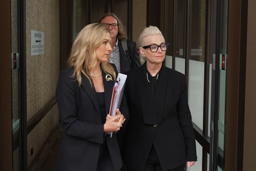 Two blonde women walk through door