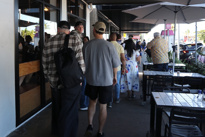 a crowd of people walking down path outside shops
