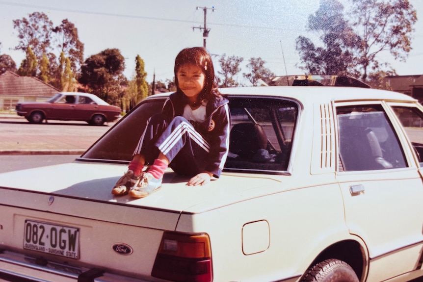 Cindy Mai as a child sitting on top of a car