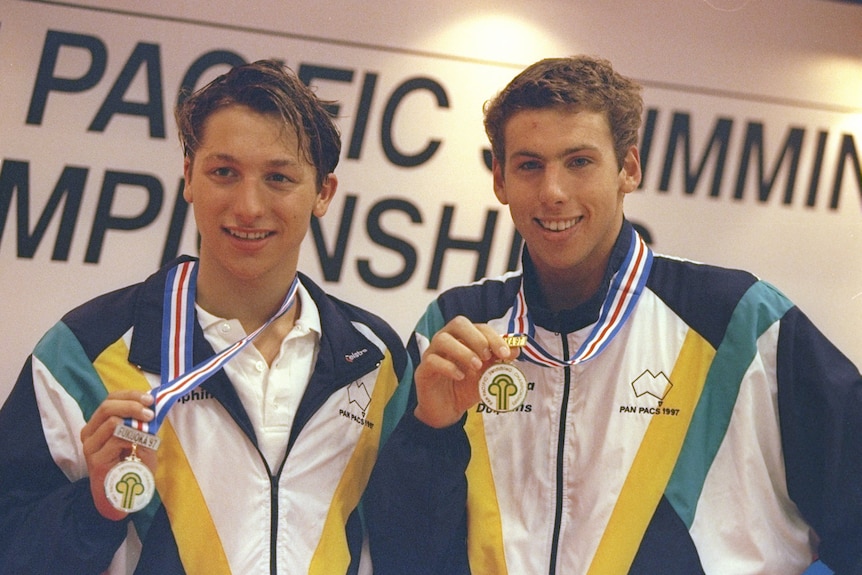 Teenaged Ian Thorpe and Grant Hackett hold up medals hanging around their necks.