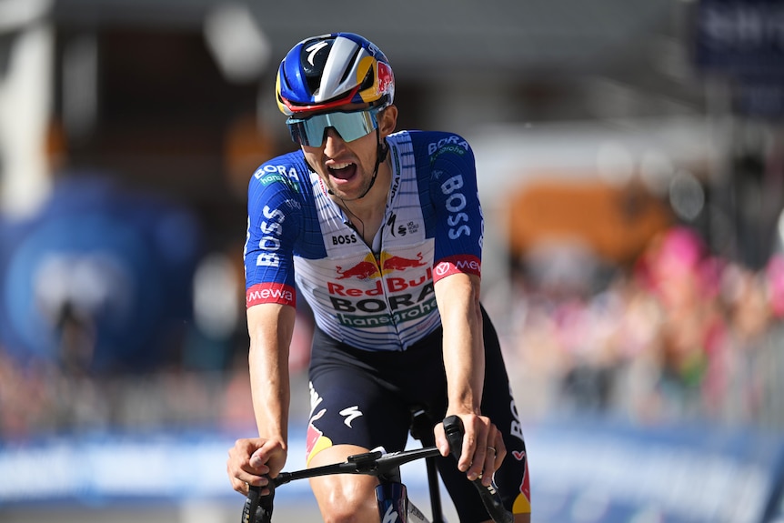 Cyclist crossing the finish line, exerting effort shown in his facial expression