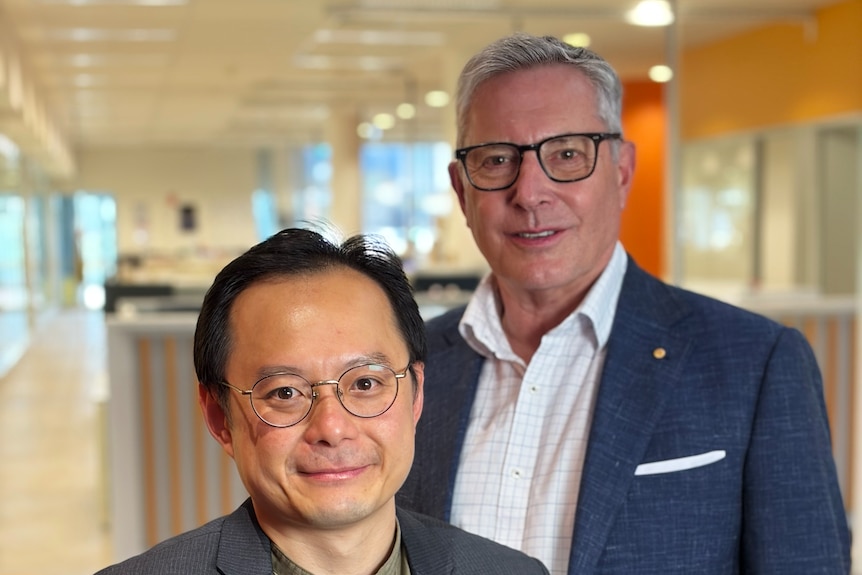 Two men, wearing business attire, smile at the camera.