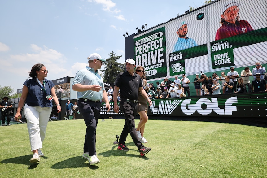 Scott O'Neil walks on the first tee box in front of LIV Golf signage