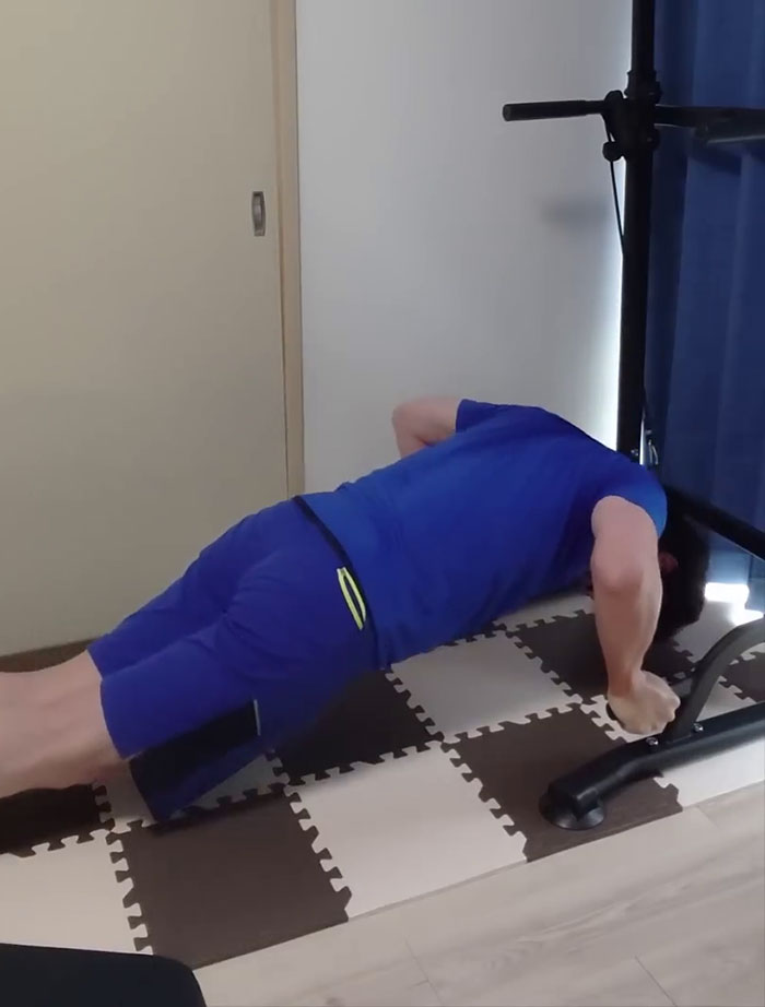 Japanese YouTuber performing push-ups on a mat as part of Saitama routine