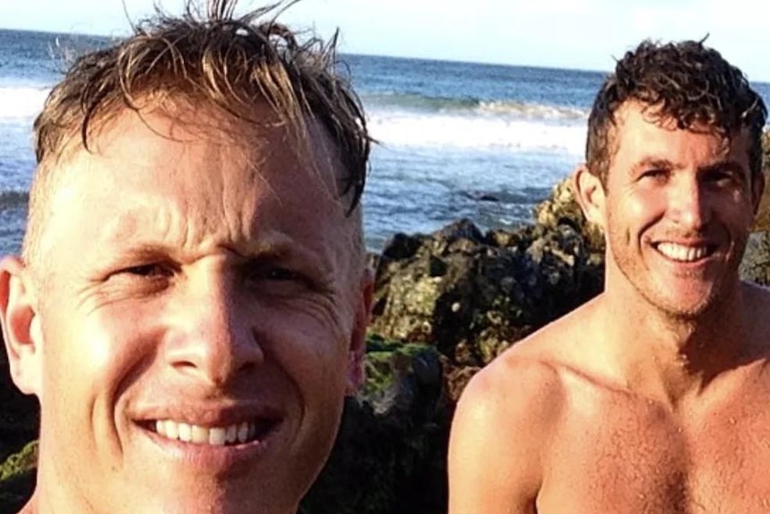 Two men in a selfie with ocean behind them